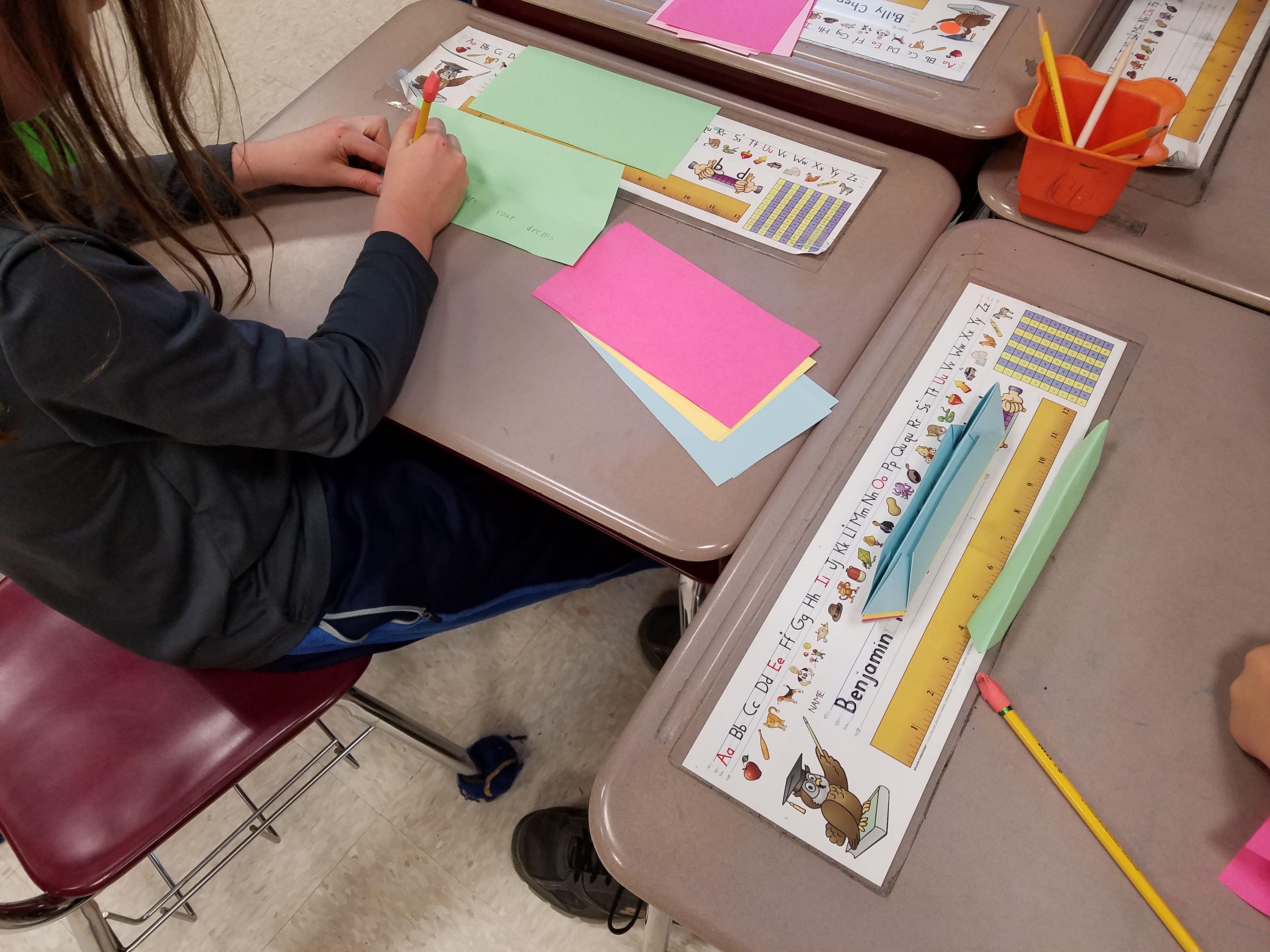 A student writes a special message on the paper before she folds it.
