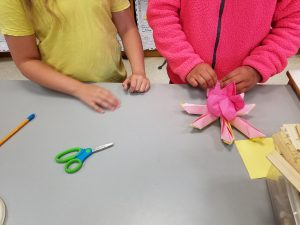 A 4th grade buddy shows a 2nd grade buddy how to create the petals of the lotus flower.